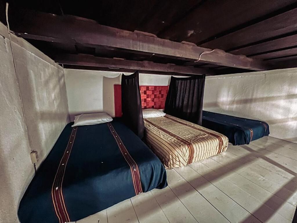 A dormitory-style room with bunk beds, a red brick accent wall, and a wooden ceiling.