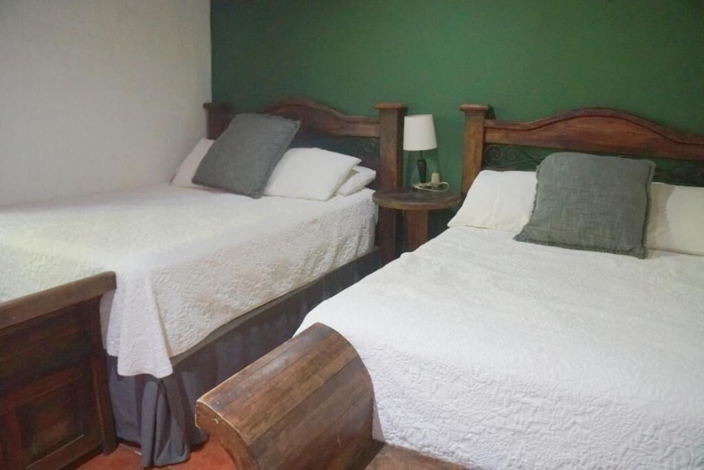 Two single beds with wooden headboards, white linens, and a bedside table with a lamp.
