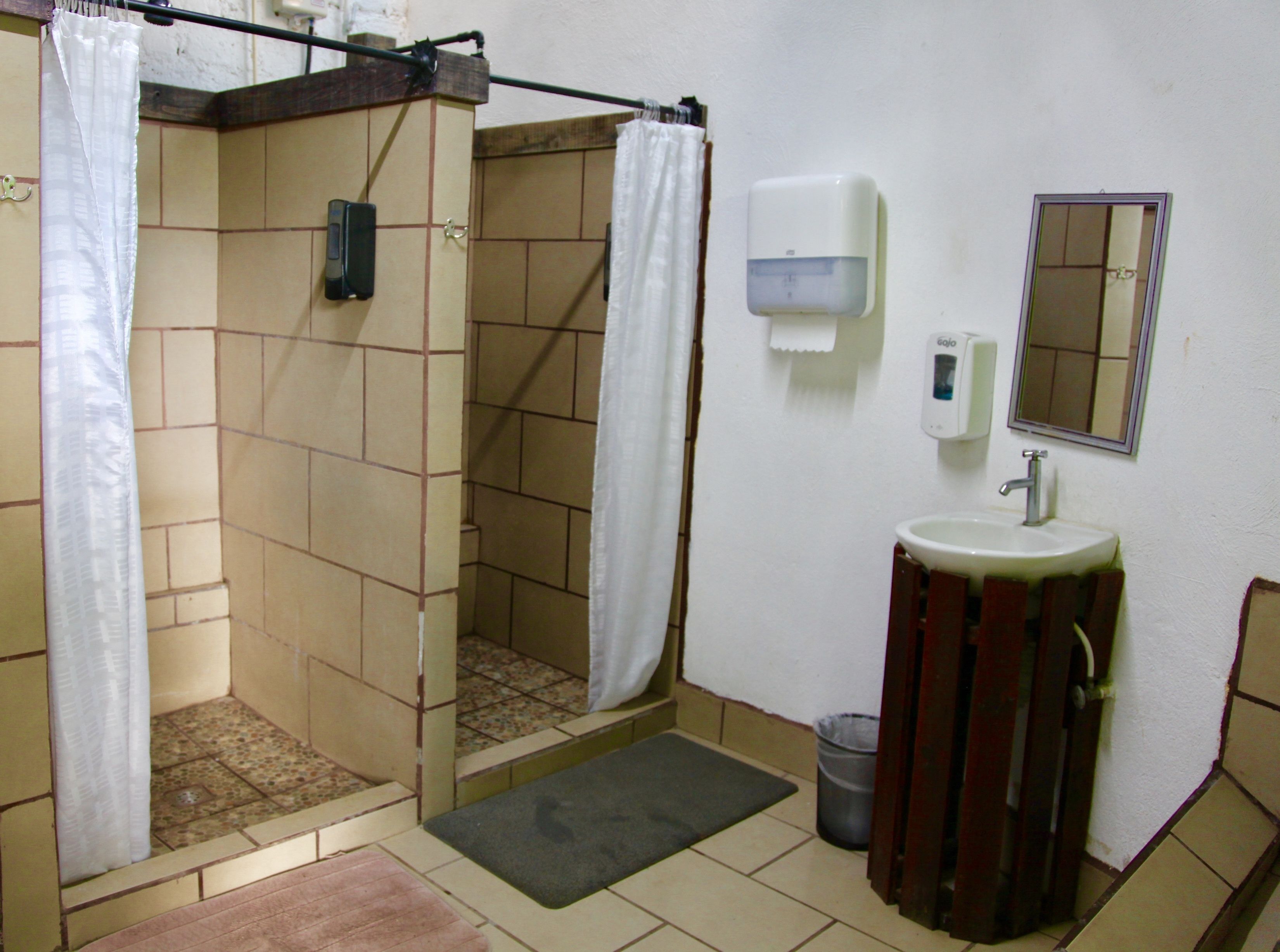 Un bagno con doccia, lavandino, specchio e asciugatore di mani.