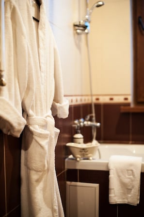 A bathroom with a white bathrobe hanging on a rack, a vintage-style sink, and a shower head. - Art Rustic Hotel (Chisinau)