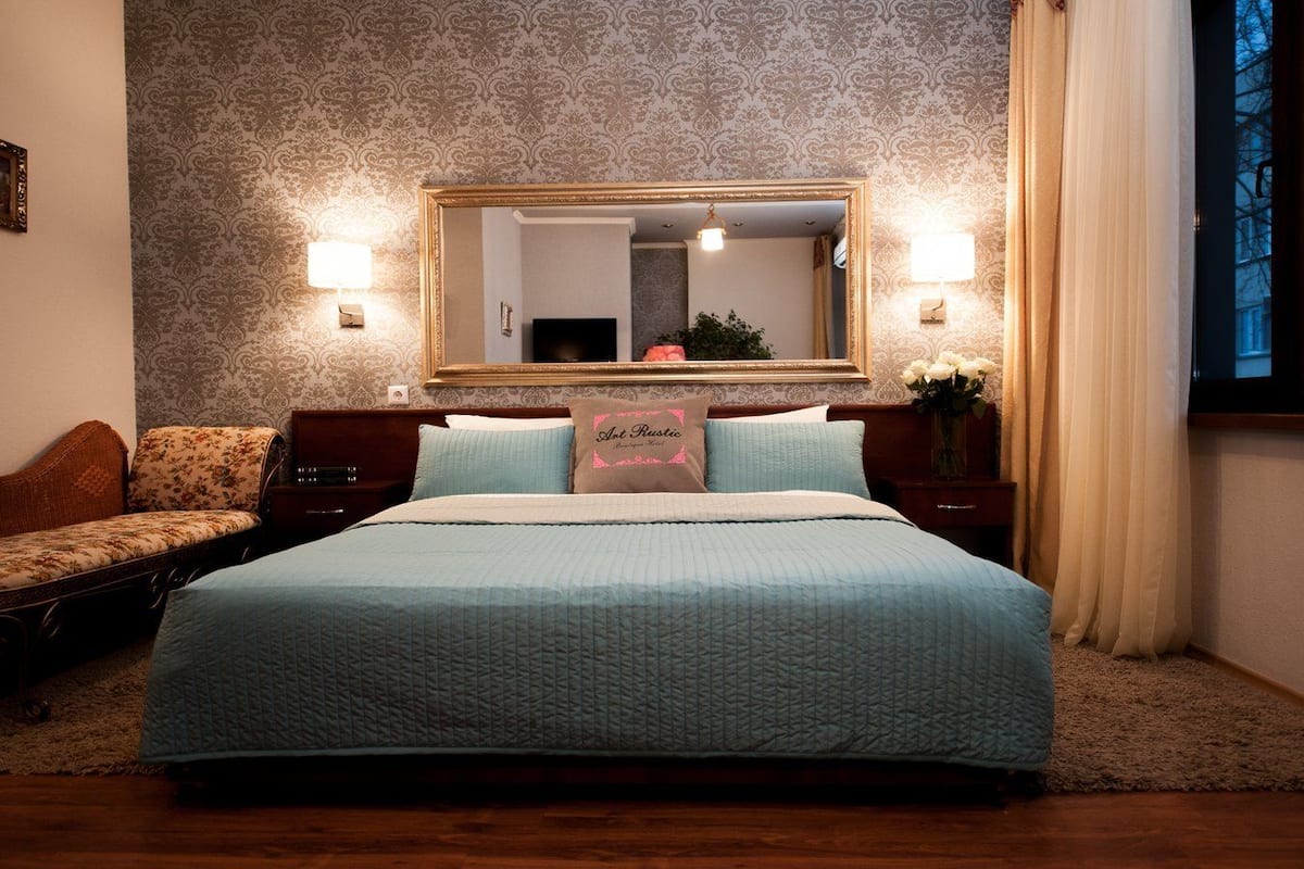 Un dormitorio con una cama grande, una mesita de noche, un espejo y un sofá.