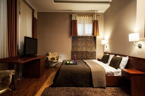 A hotel room with a bed, a desk, a chair, a TV, and a brick wall. - Art Rustic Hotel (Chisinau)