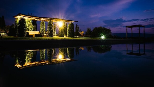 A tranquil lakeside setting with a gazebo, a bench, and a pool reflecting the structure.
