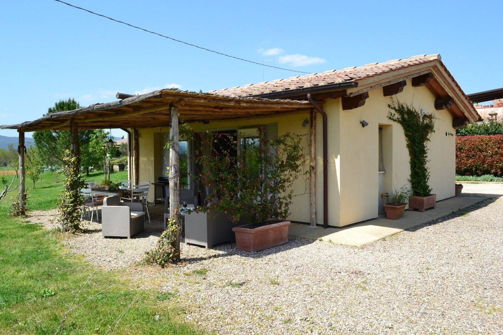 A house with a covered patio, outdoor furniture, and potted plants.