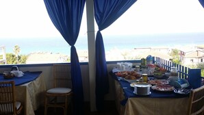 A balcony with a table set for breakfast overlooking the sea. - B&B Villa Betta (Bonifati)