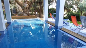 An outdoor swimming pool with clear blue water, surrounded by wooden deck and lounge chairs. - B&B Villa Betta (Bonifati)