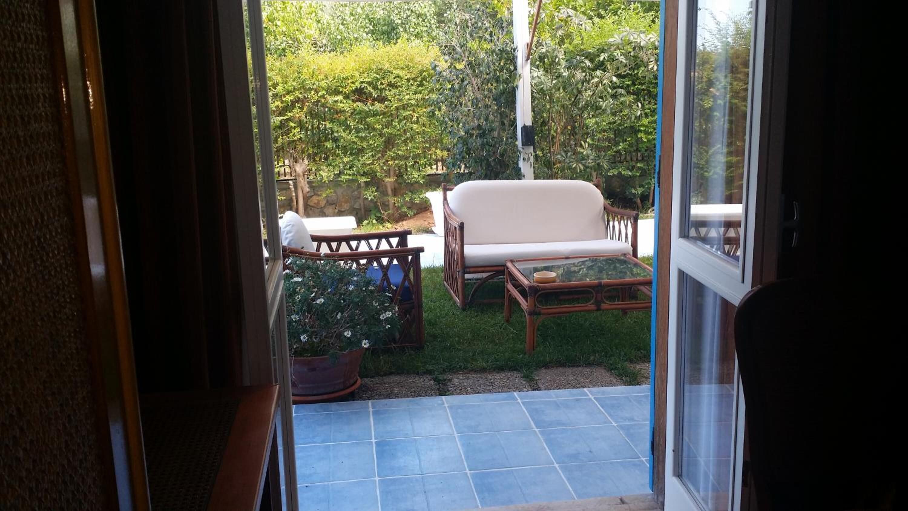Un espace patio avec un canapé blanc, une table en osier et une plante en pot.