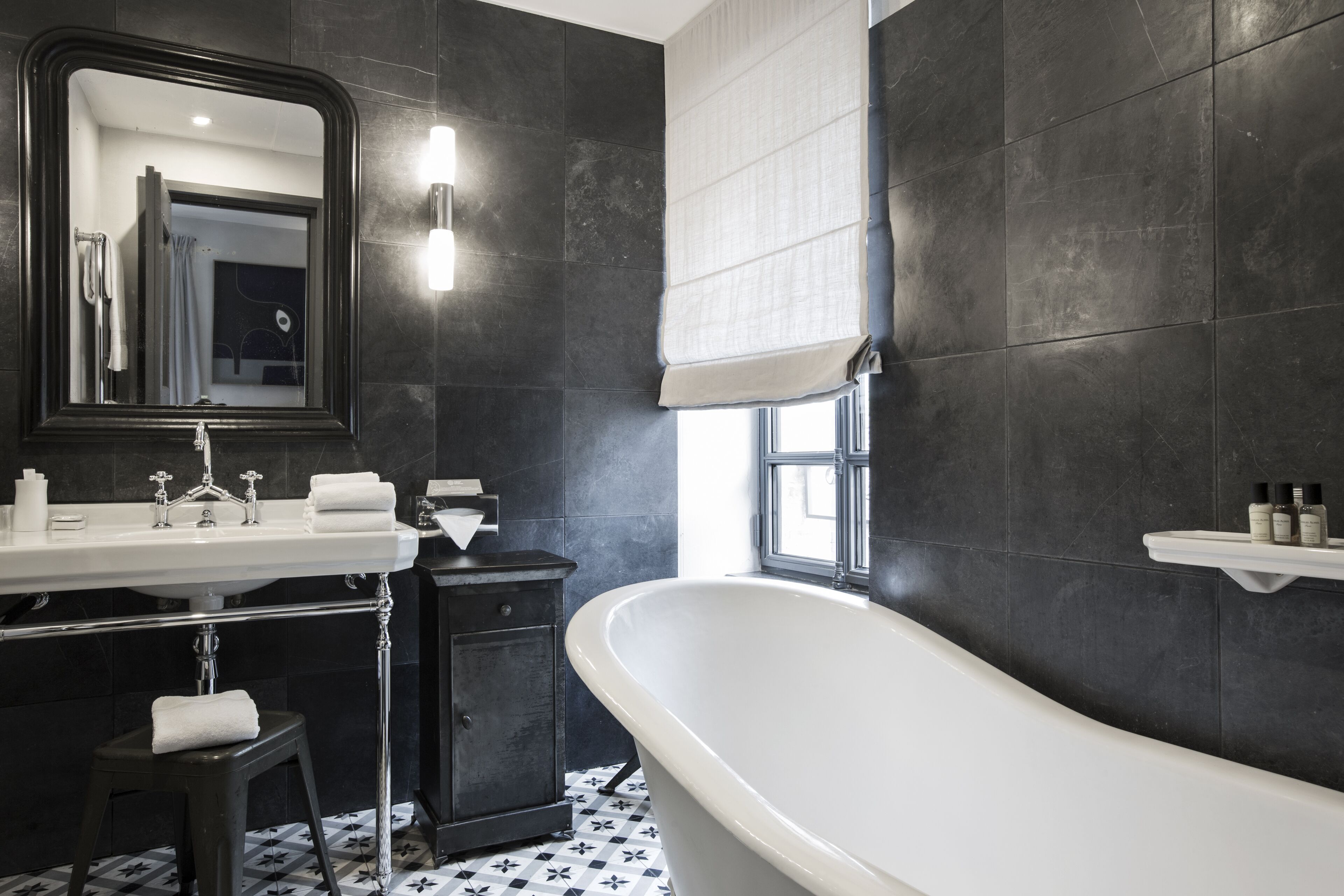 A modern bathroom with a freestanding bathtub, a large mirror, and a vanity with a sink and towel rack.