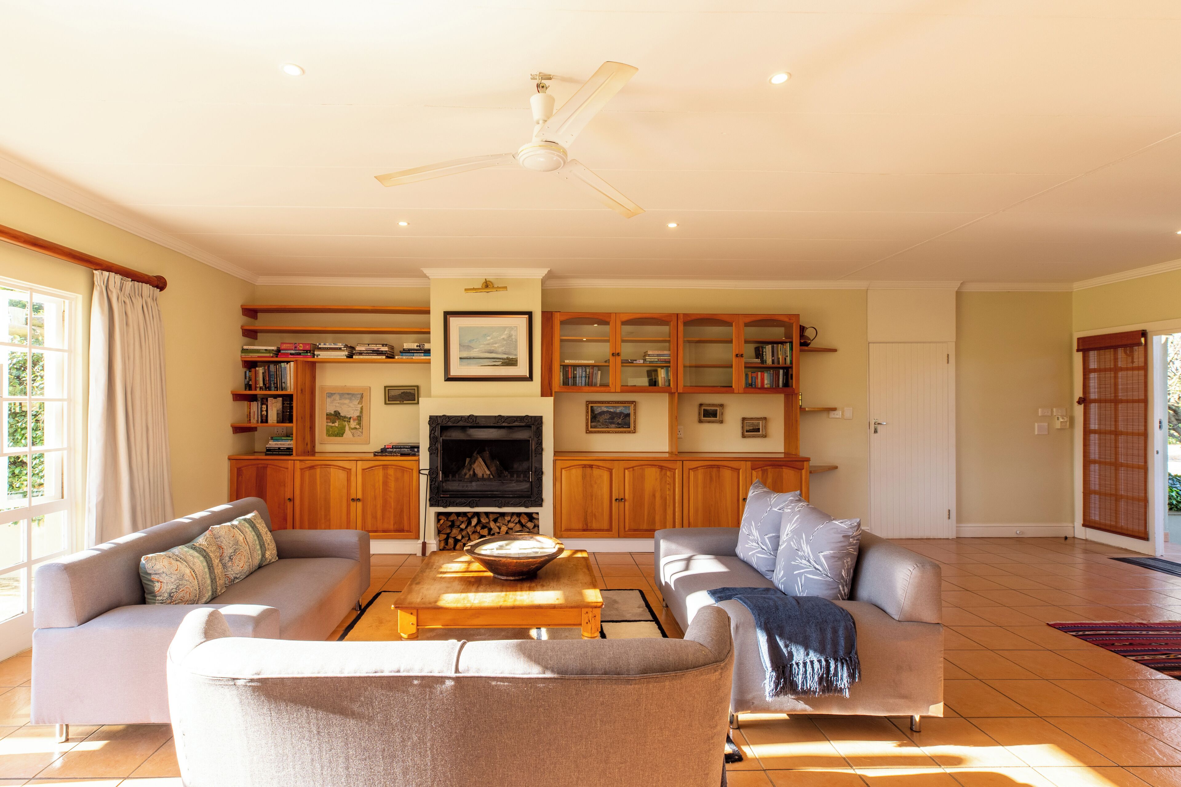 A spacious living room with a fireplace, two sofas, a coffee table, and a ceiling fan.