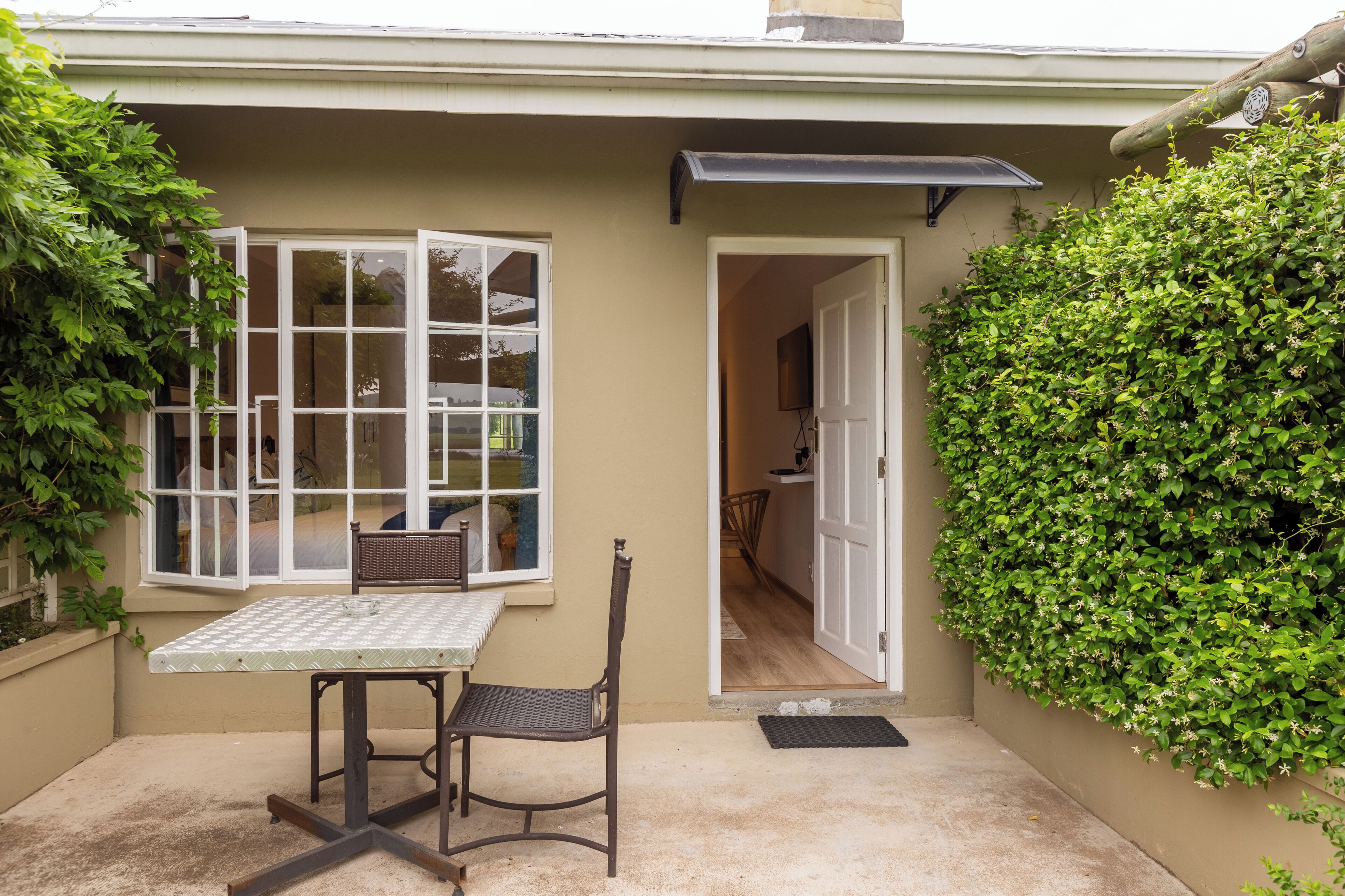 Une petite terrasse avec une table et une chaise, une fenêtre et une porte donnant sur un espace intérieur.
