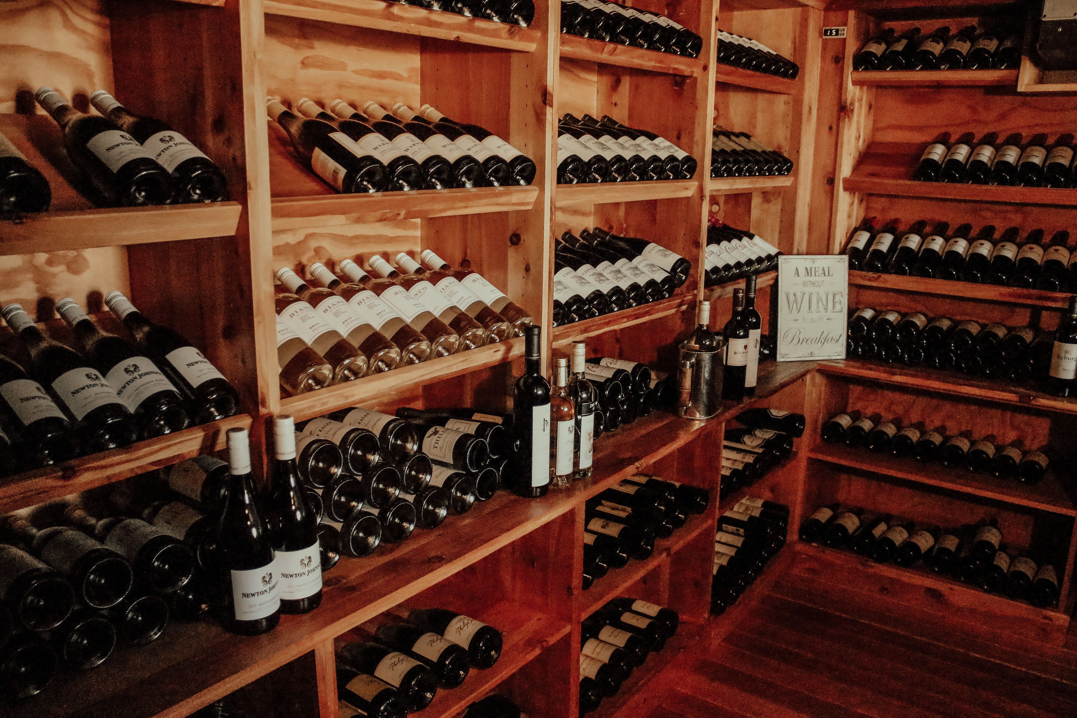 A wine cellar with wooden shelves stocked with various wine bottles.