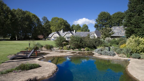 A house with a swimming pool, surrounded by a well-maintained lawn and trees. - Moorcroft Manor Boutique Country Hotel (Himeville)