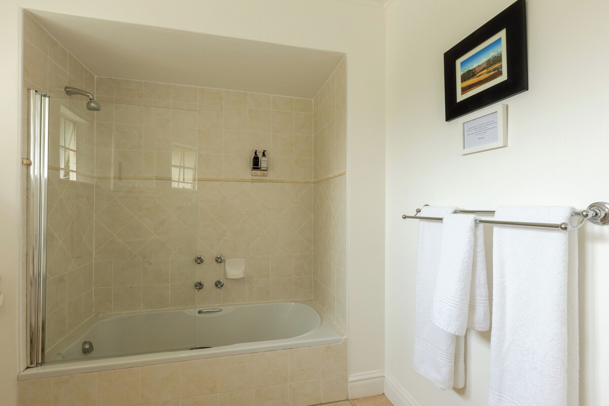A modern bathroom with a glass-enclosed shower, a freestanding bathtub, and a towel rack with white towels.