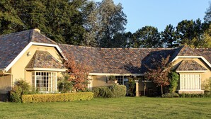 A two-story house with a sloped roof, a front porch, and a well-maintained lawn. - Moorcroft Manor Boutique Country Hotel (Himeville)