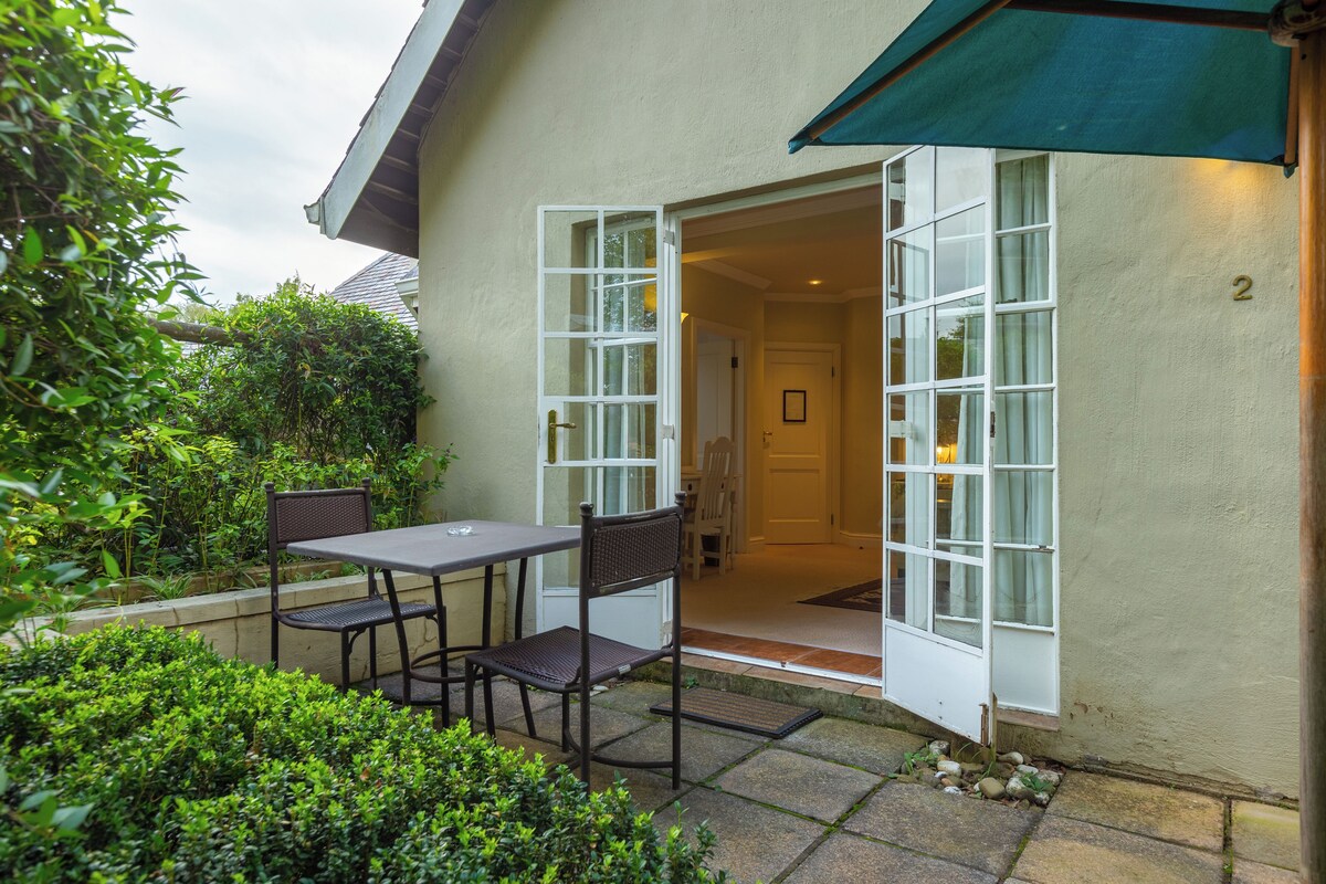 An outdoor patio with a table and chairs, a door leading to a room, and a number '2' on the wall.