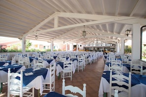 An indoor dining area with white tables and chairs, arranged in rows under a white ceiling structure. - Club Hotel Marina Seada Beach (Budoni)