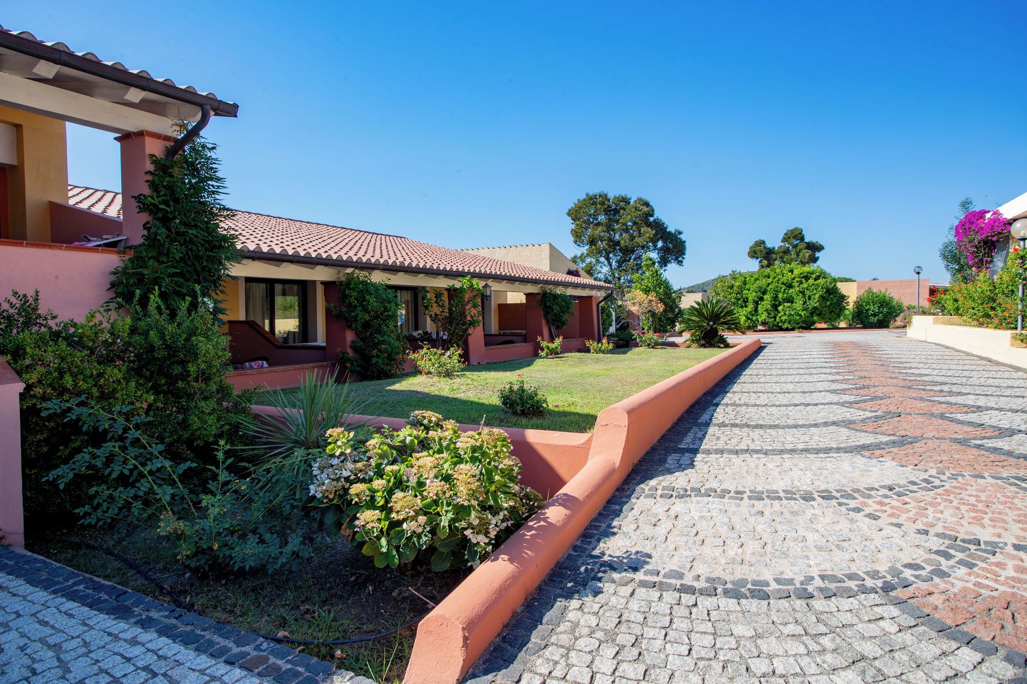 A house with a tiled roof, a paved driveway, and a well-maintained garden.