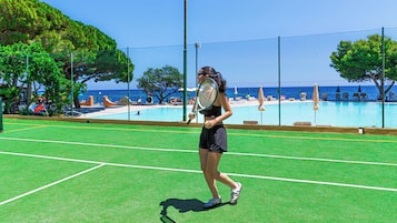 Een tennisbaan met een zwembad op de achtergrond.