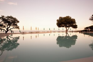 A tranquil infinity pool reflecting trees and umbrellas, with a clear view of the sea. - Club Hotel Marina Seada Beach (Budoni)