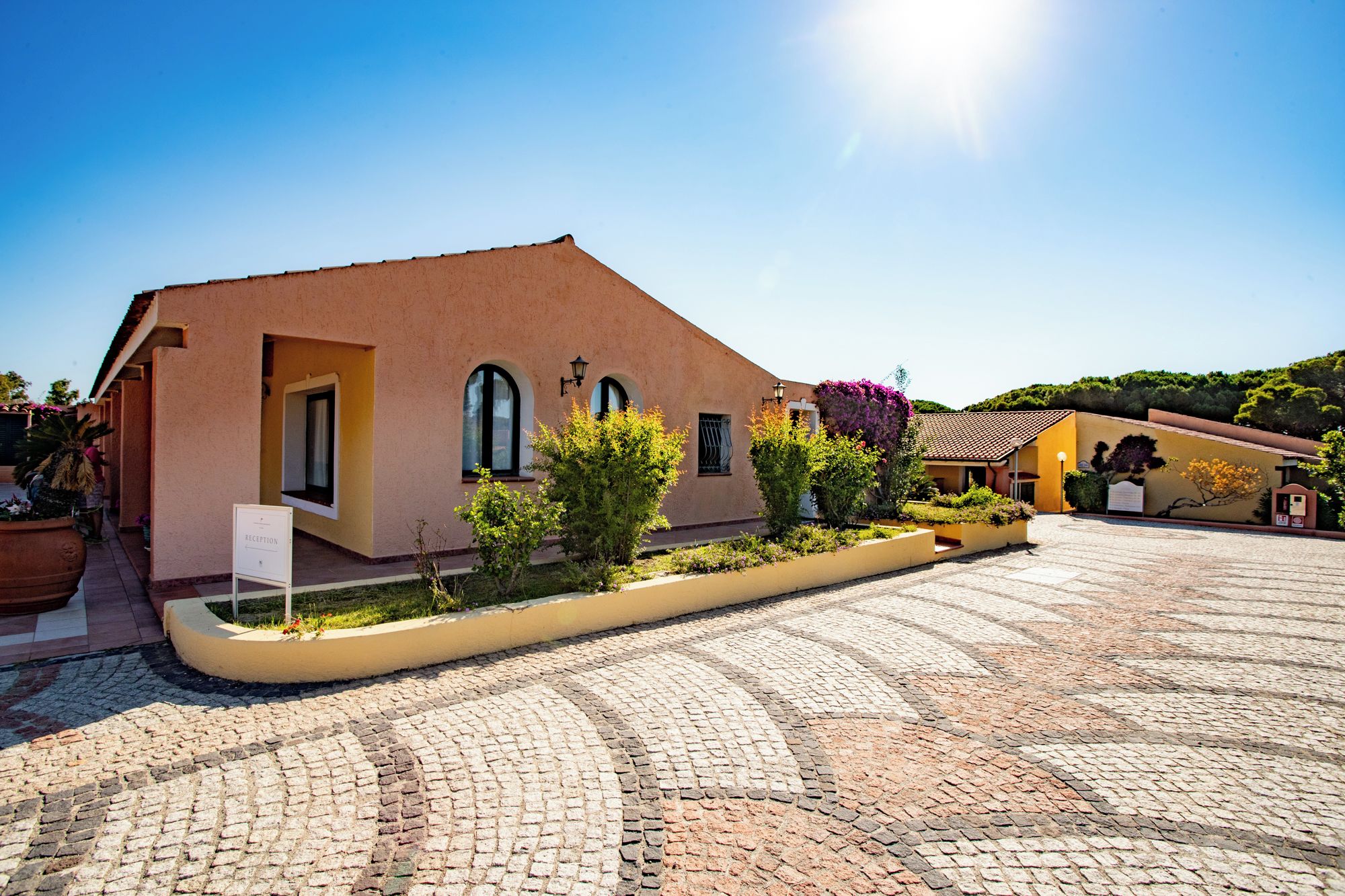 A building with a reception area, a paved courtyard, and a clear sky.
