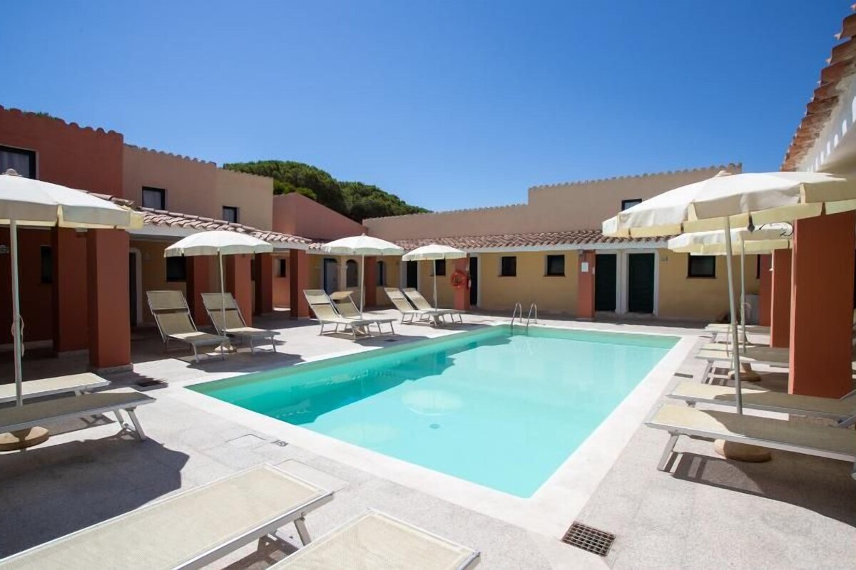A pool area with lounge chairs and umbrellas, surrounded by buildings with a consistent architectural style.
