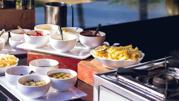 Diverse schalen met eten op een tafel, met een uitzicht op een waterpartij op de achtergrond.