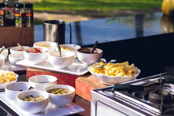 A variety of food bowls on a table with a view of a body of water in the background. - Black Thunder (METTUPALAYAM)