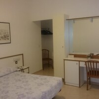 A bedroom with a bed, a desk, a chair, and a wardrobe.