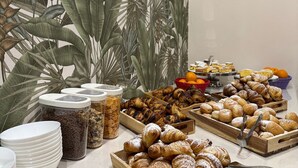 A buffet with various baked goods, including pastries and bread, and a wall with vintage food advertisements. - Hotel Eureka (Rimini)