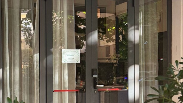 A hotel entrance with a glass door, a red mat, and a sign indicating emergency contact information. - Hotel Eureka (Rimini)
