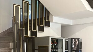 A modern interior with a staircase leading to a second floor, a vending machine, and a wall-mounted control panel. - Hotel Eureka (Rimini)