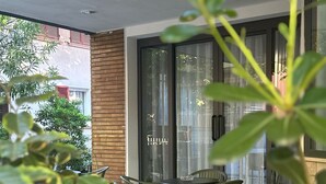 A patio with a table and chairs, a sliding glass door, and a view of the street. - Hotel Eureka (Rimini)