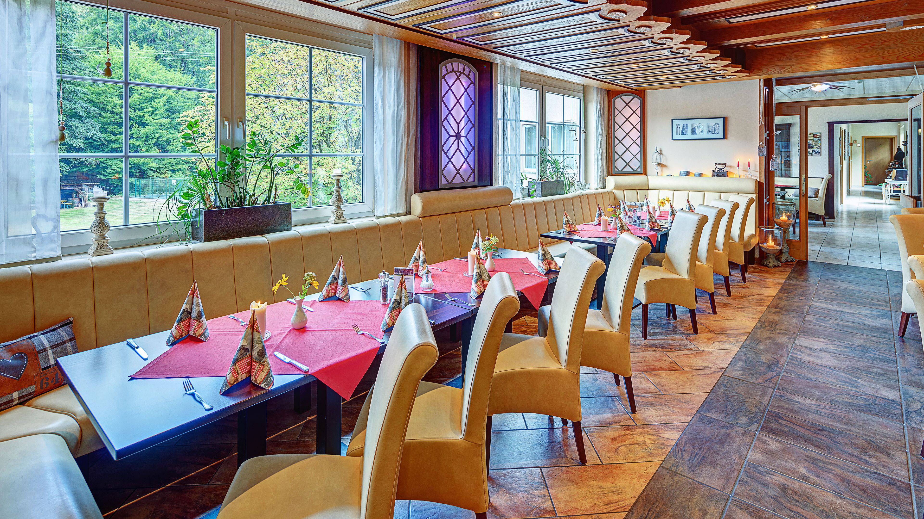 A restaurant with long tables, chairs, and a view of the outdoors.