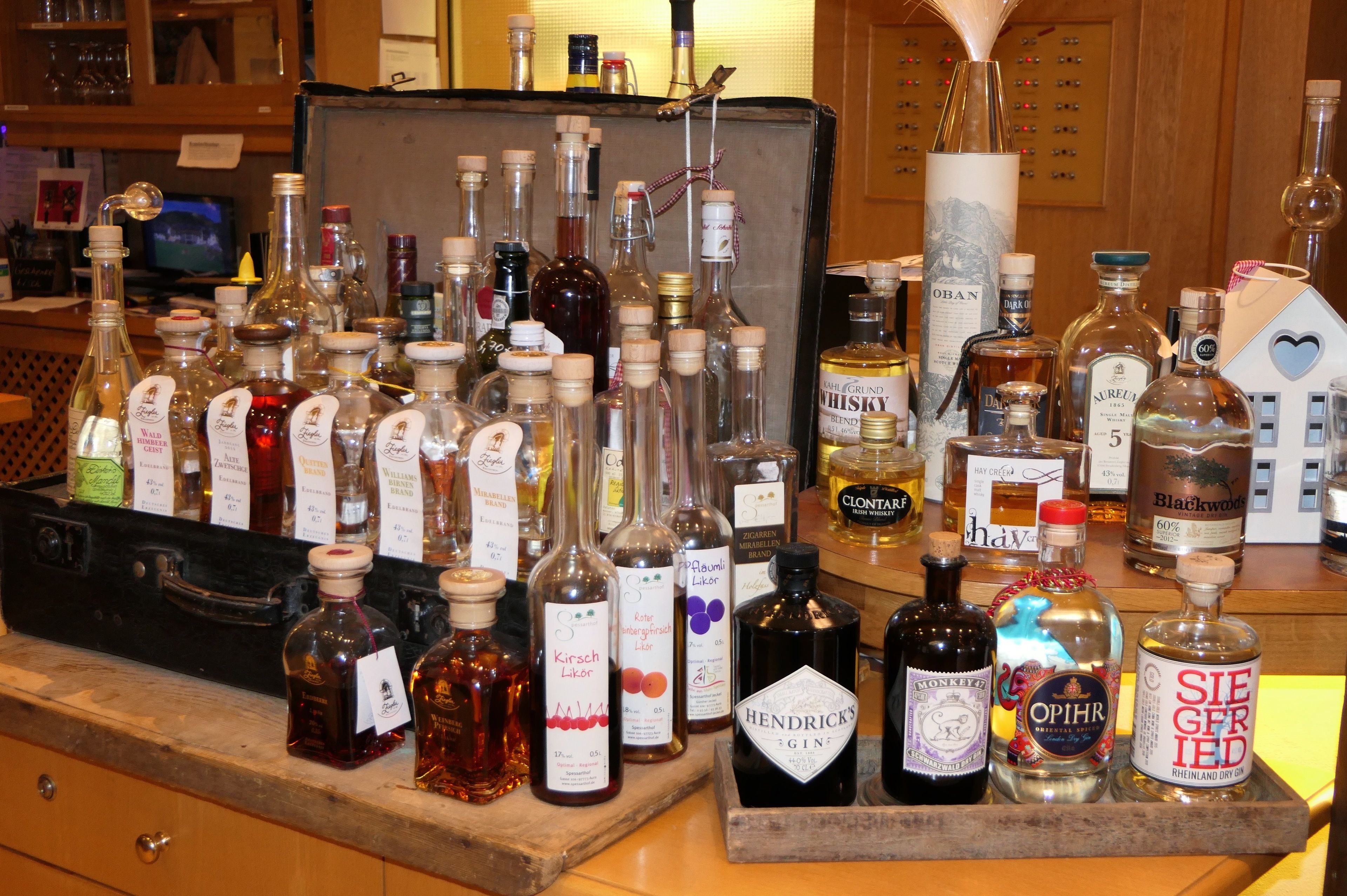 Variedad de botellas de licor expuestas sobre una barra de madera en un bar.
