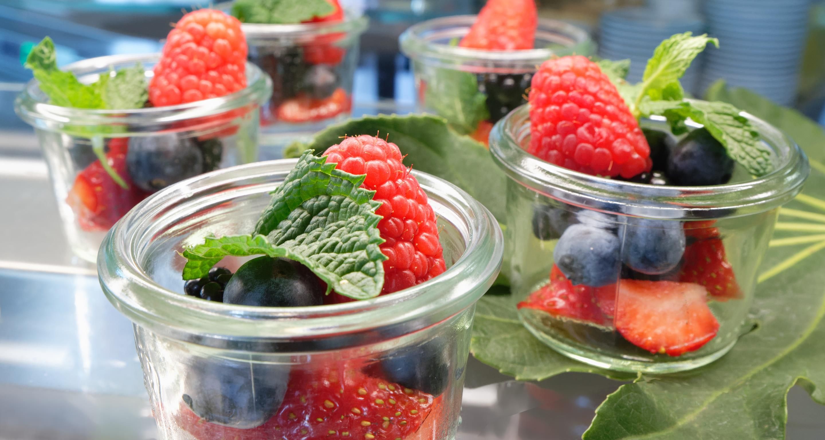 Clear glass containers with fresh berries and mint leaves.