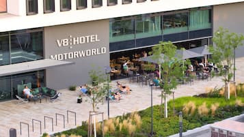 A hotel exterior with outdoor seating and a garden area.