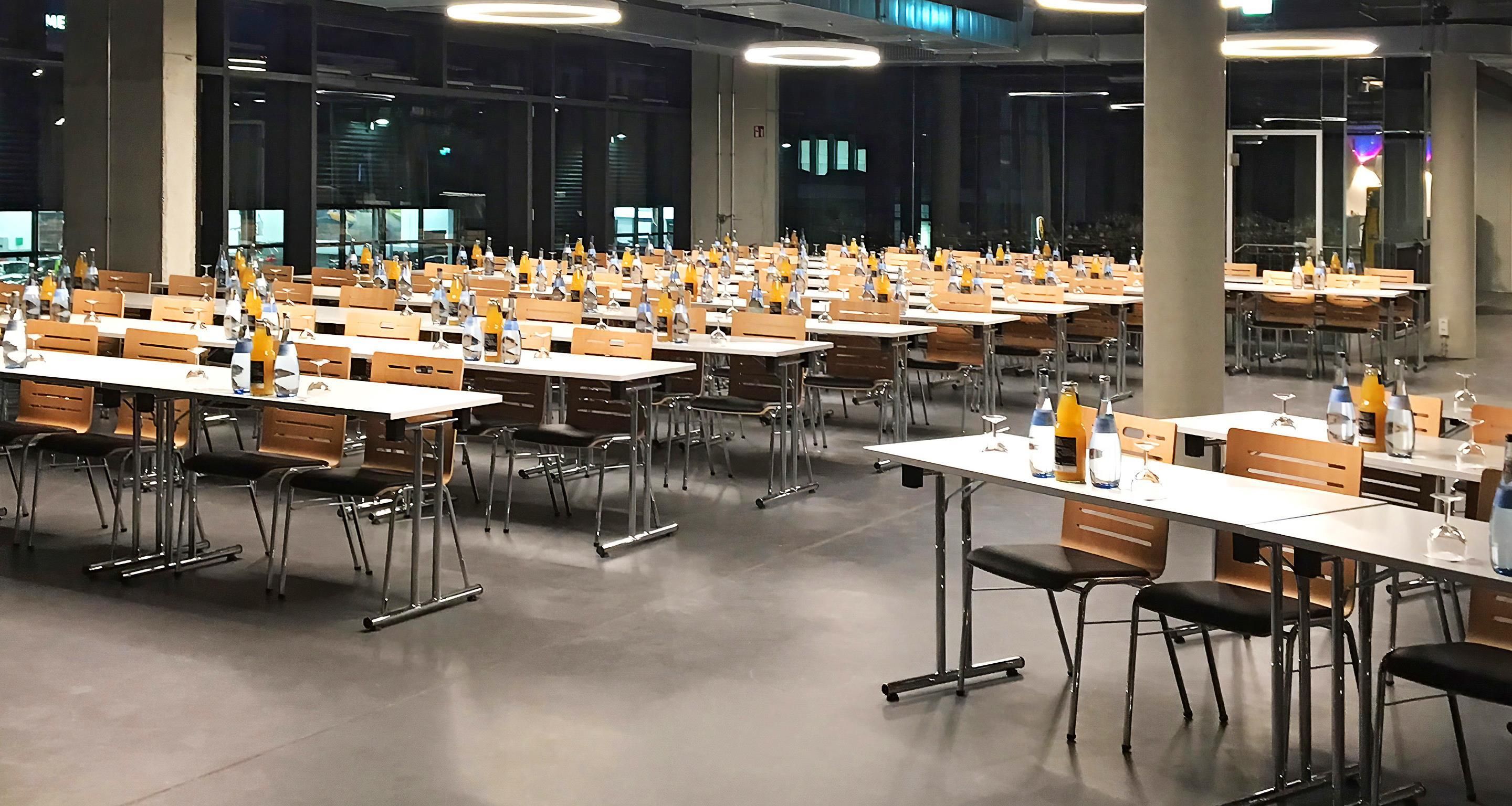 A large indoor dining area with multiple tables and chairs, arranged in rows.