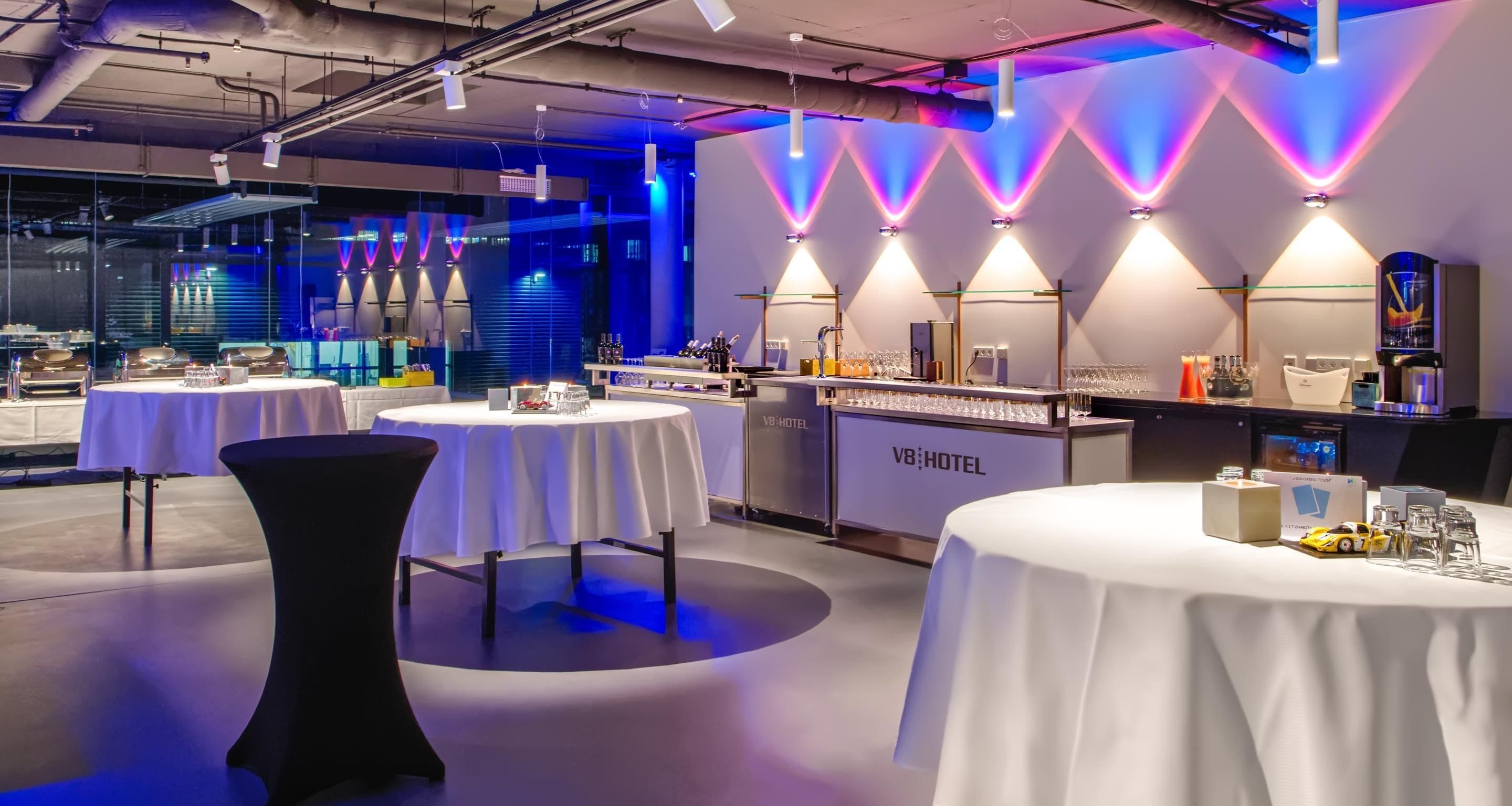 Eine moderne Hotelbar mit runden Tischen, einer Theke und gedämpfter Beleuchtung.
