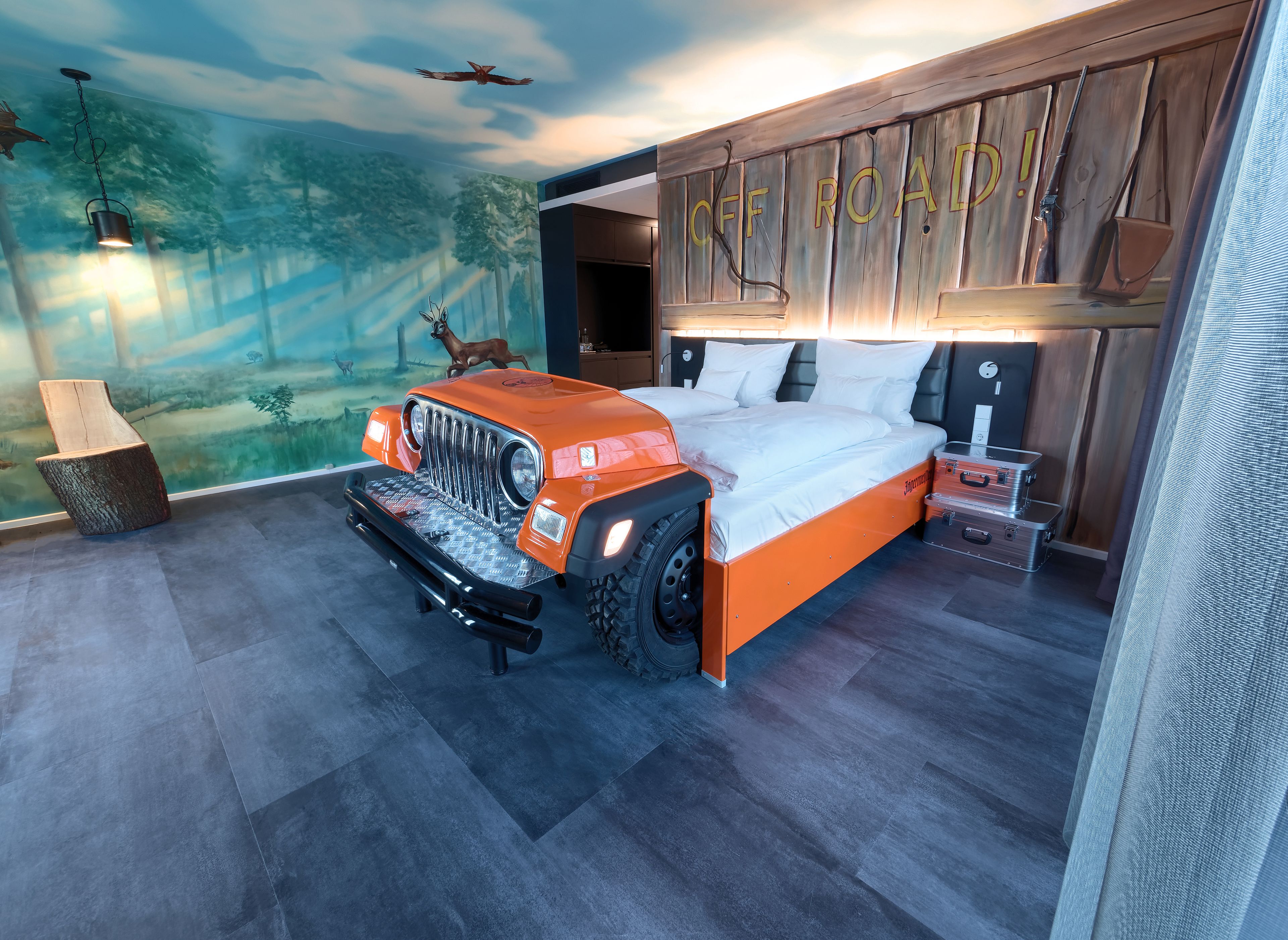 A bedroom with a Jeep bed frame, a forest mural, and a 'OFF ROAD!' sign on the wall.