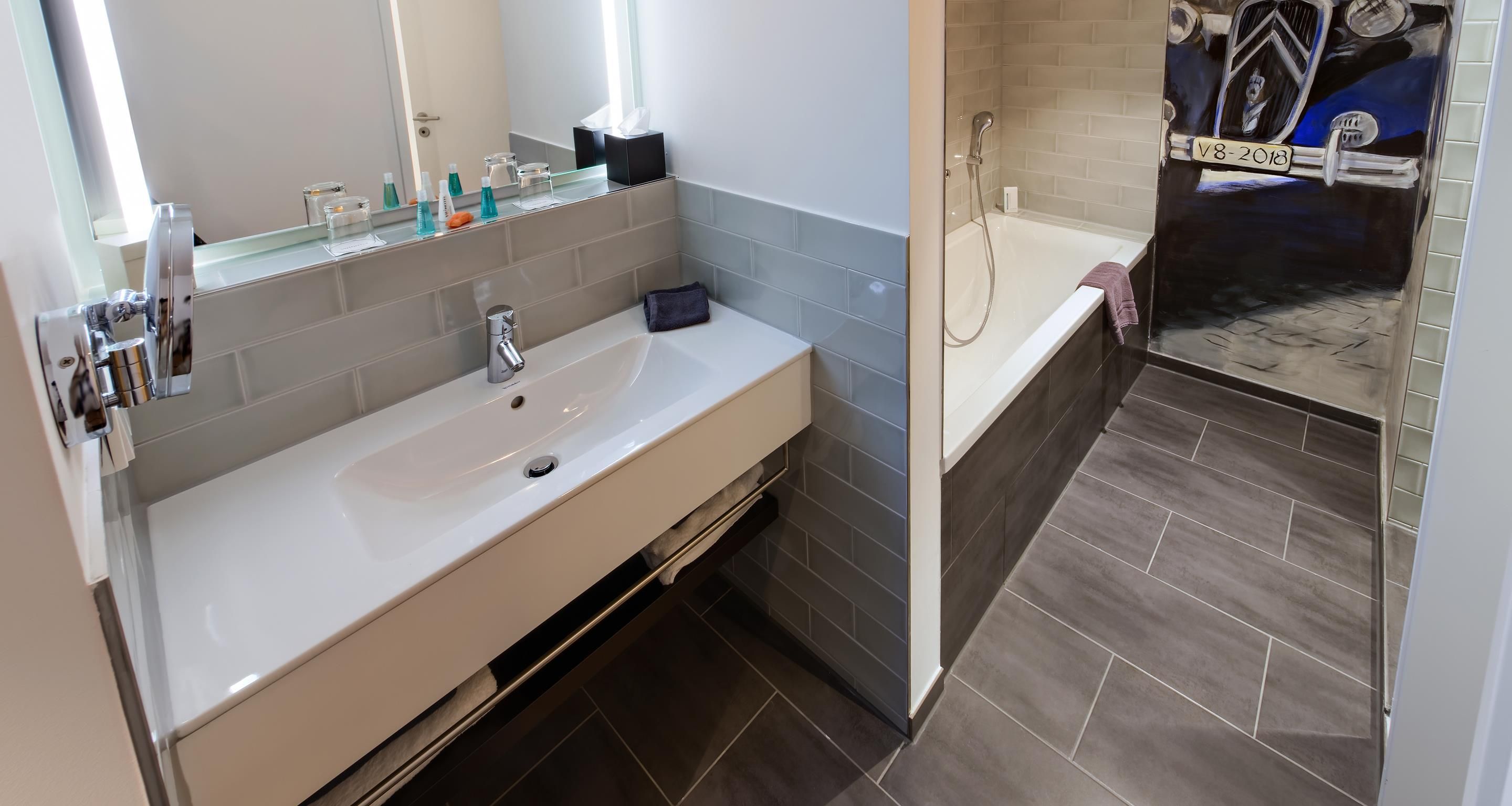 A modern bathroom with a white sink, mirror, and a shower area.