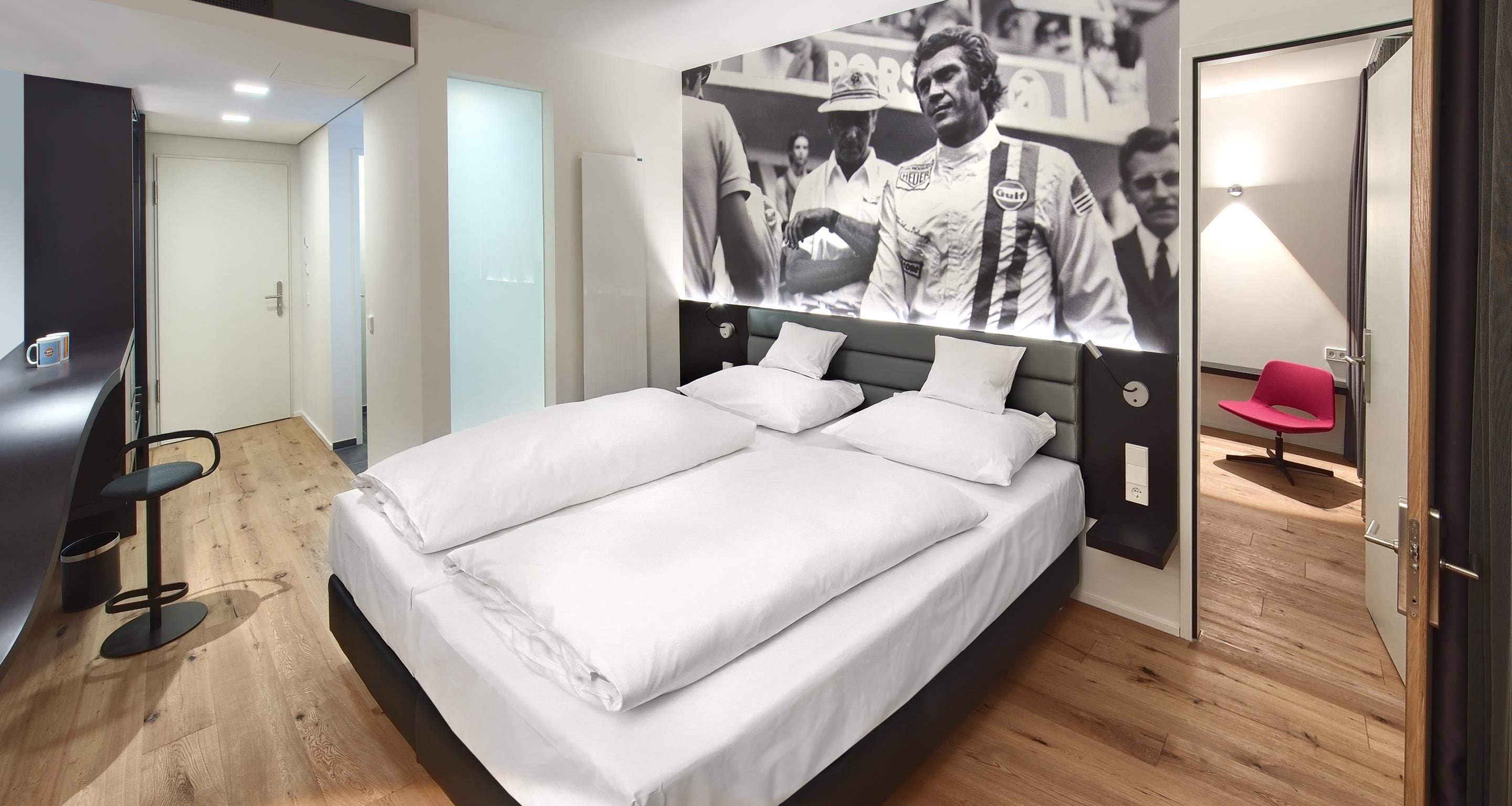 A modern hotel room with a large bed, a desk, and a chair.