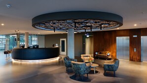 A modern reception area with a circular desk, plush seating, and a unique ceiling design. - V8 Hotel Motorworld Region Stuttgart, BW Premier Collection (Boeblingen)