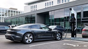 A modern building with large glass windows and a parking area with electric vehicle charging stations. - V8 Hotel Motorworld Region Stuttgart, BW Premier Collection (Boeblingen)