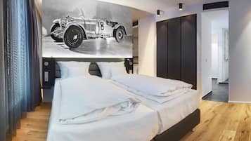 A modern bedroom with a large bed, a headboard with integrated lighting, a wall-mounted artwork of a vintage car, and a walk-in closet.
