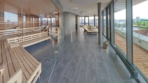 A modern balcony with wooden seating, large windows, and a view of a river and cityscape. - V8 Hotel Motorworld Region Stuttgart, BW Premier Collection (Boeblingen)