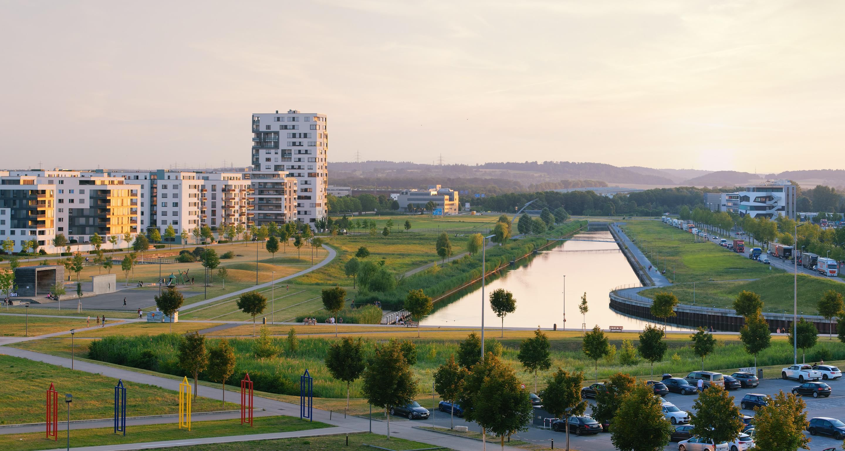 Un paisaje urbano moderno con edificios residenciales, un río y un área de estacionamiento.