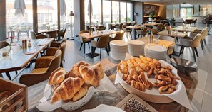 A dining area with tables, chairs, and a variety of pastries. - V8 Hotel Motorworld Region Stuttgart, BW Premier Collection (Boeblingen)
