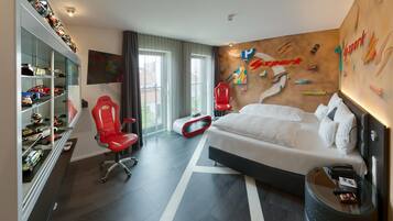 Ein Hotelzimmer mit Bett, Schreibtisch, Stuhl, Fernseher und einer Wand mit Kletterwand-Motiv.