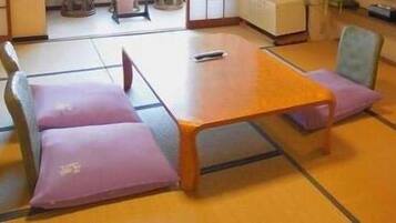 Ein Raum mit Tatami-Matten, einem niedrigen Holztisch und zwei Kissen.