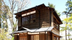 A two-story wooden building with large windows and a balcony.